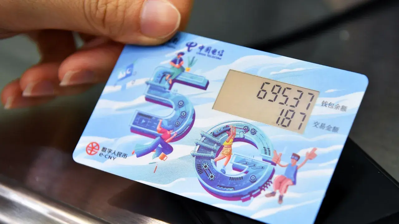 Carta con display mostra saldo e transazione, con icone che celebrano il yuan digitale e la tecnologia 5G.