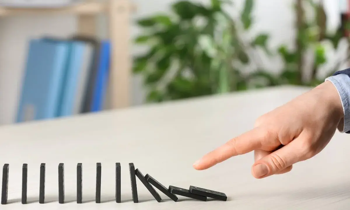 Dita che spingono tessere del domino, innescando una reazione a catena. Il "nudge significato" è proprio questo: un piccolo impulso che genera un grande effetto.