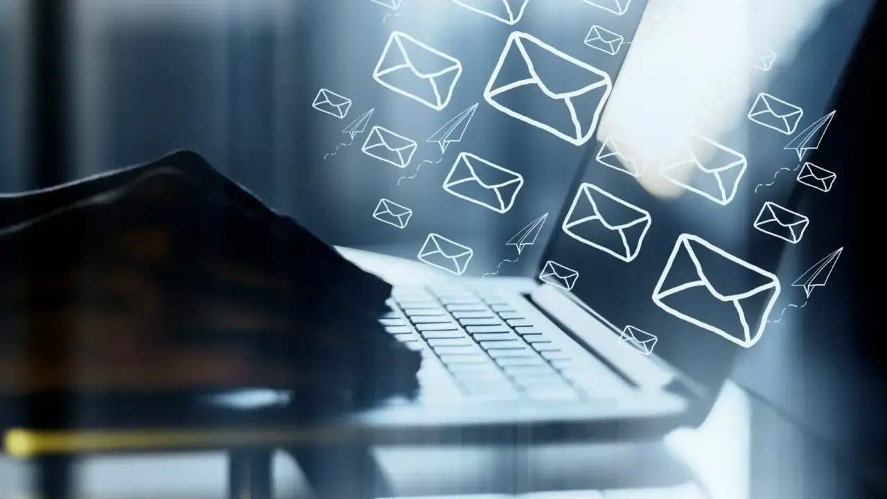 Mani su tastiera di laptop, con tante email e aeroplanini di carta che volano, come un email da me stesso con ricatto.