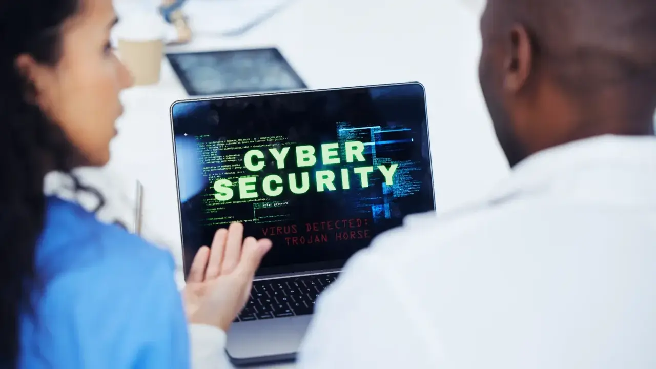 Due professionisti analizzano un avviso di sicurezza informatica su un laptop: "VIRUS DETECTED: TROJAN HORSE".