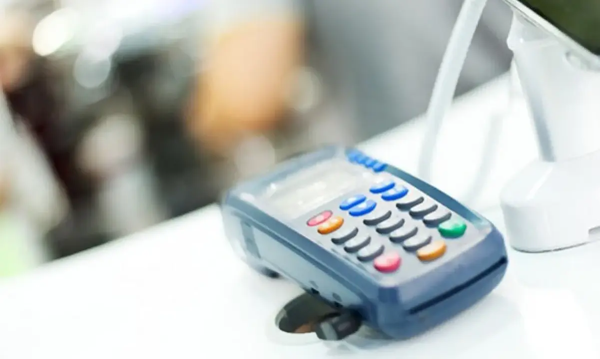 POS per chi non è obbligatorio. Un lettore di carte di credito su un bancone bianco, con uno schermo e tasti colorati.