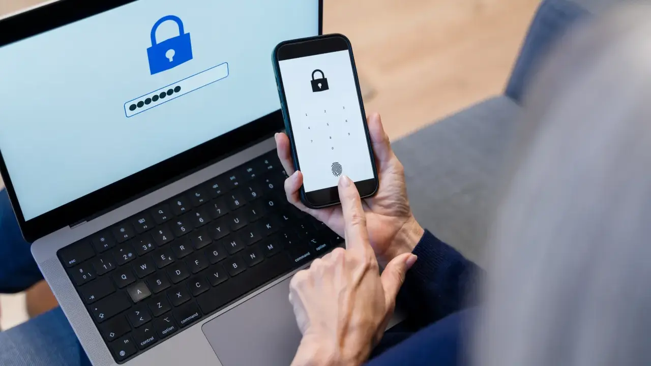 Persona usa smartphone e laptop per accedere a un account. Un password manager cos'è? È uno strumento per gestire le password in modo sicuro.