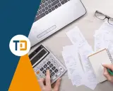 Scrivania con laptop, calcolatrice, occhiali e ricevute. Una mano scrive su un quaderno, forse per una nota credito per errata fatturazione.