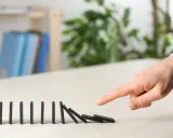 Dita che spingono tessere del domino, innescando una reazione a catena. Il "nudge significato" è proprio questo: un piccolo impulso che genera un grande effetto.
