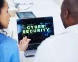 Due professionisti analizzano un avviso di sicurezza informatica su un laptop: "VIRUS DETECTED: TROJAN HORSE".