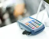 POS per chi non è obbligatorio. Un lettore di carte di credito su un bancone bianco, con uno schermo e tasti colorati.