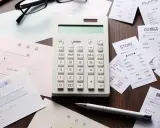 Calcolatrice e ricevute sparse, un promemoria visivo di una possibile multa per scontrino non emesso.
