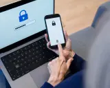 Persona usa smartphone e laptop per accedere a un account. Un password manager cos'è? È uno strumento per gestire le password in modo sicuro.