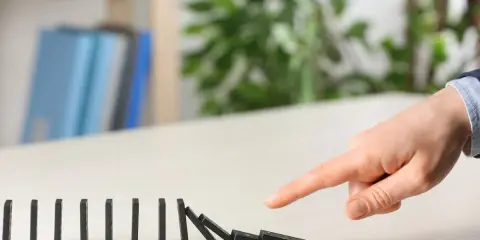 Dita che spingono tessere del domino, innescando una reazione a catena. Il "nudge significato" è proprio questo: un piccolo impulso che genera un grande effetto.