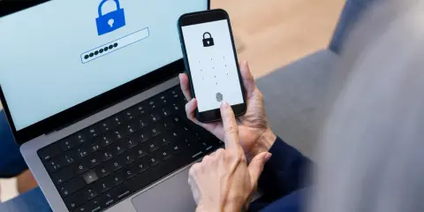 Persona usa smartphone e laptop per accedere a un account. Un password manager cos'è? È uno strumento per gestire le password in modo sicuro.