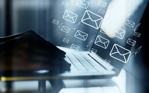 Mani su tastiera di laptop, con tante email e aeroplanini di carta che volano, come un email da me stesso con ricatto.