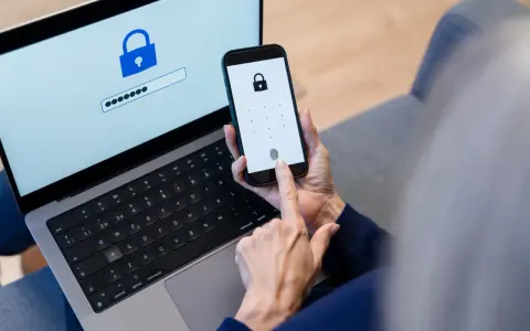 Persona usa smartphone e laptop per accedere a un account. Un password manager cos'è? È uno strumento per gestire le password in modo sicuro.