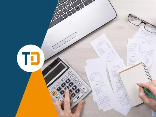 Scrivania con laptop, calcolatrice, occhiali e ricevute. Una mano scrive su un quaderno, forse per una nota credito per errata fatturazione.