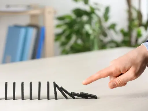 Dita che spingono tessere del domino, innescando una reazione a catena. Il "nudge significato" è proprio questo: un piccolo impulso che genera un grande effetto.