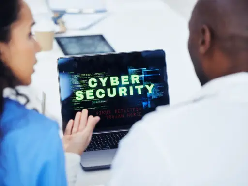 Due professionisti analizzano un avviso di sicurezza informatica su un laptop: "VIRUS DETECTED: TROJAN HORSE".
