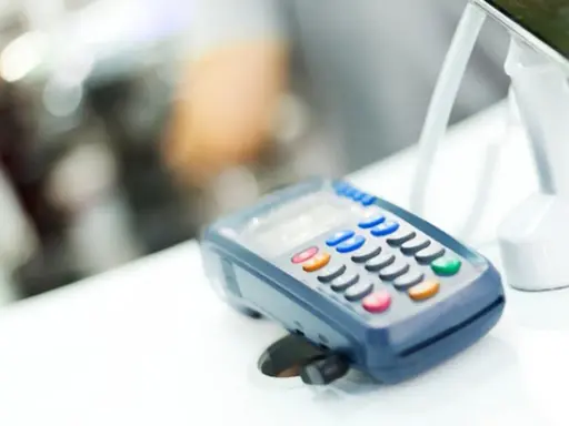 POS per chi non è obbligatorio. Un lettore di carte di credito su un bancone bianco, con uno schermo e tasti colorati.