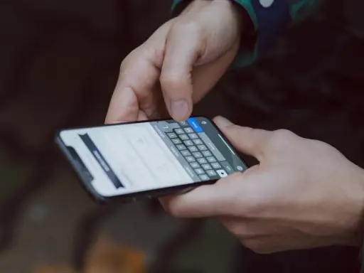 Mani che digitano su uno smartphone, con la tastiera visibile. Come accorgersi di trojan intercettazioni? Attenzione ai segnali insoliti.