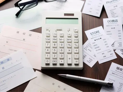 Calcolatrice e ricevute sparse, un promemoria visivo di una possibile multa per scontrino non emesso.