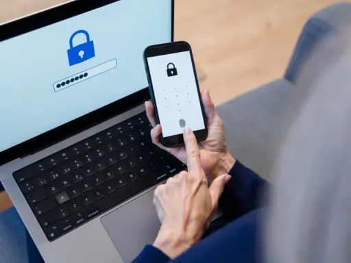 Persona usa smartphone e laptop per accedere a un account. Un password manager cos'è? È uno strumento per gestire le password in modo sicuro.