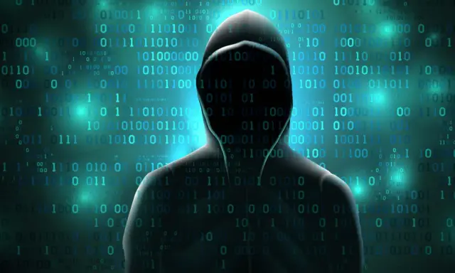 Silhouette di hacker su sfondo di codice binario. Attenzione alle criptovalute da evitare.