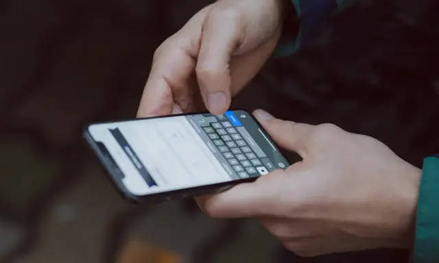 Mani che digitano su uno smartphone, con la tastiera visibile. Come accorgersi di trojan intercettazioni? Attenzione ai segnali insoliti.