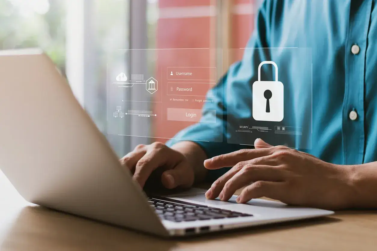 Un uomo digita su un laptop, con un'interfaccia di login e un lucchetto che simboleggiano l'importanza dell'igiene informatica per la sicurezza dei dati.