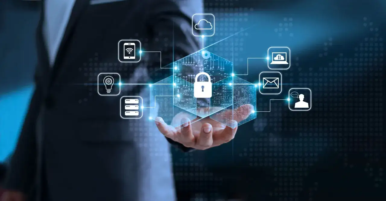 Un uomo in giacca e cravatta tiene in mano un esagono luminoso con un lucchetto, simbolo di sicurezza. Icone di cloud, smartphone, lampadina, server, laptop, email e persona con fumetto si collegano ad esso, rappresentando la protezione contro ogni cyb...