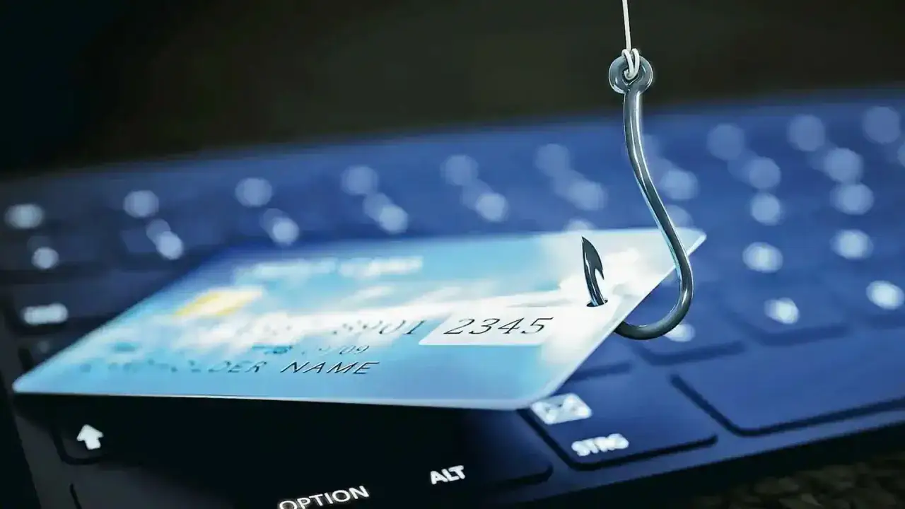 Un amo da pesca aggancia una carta di credito su una tastiera, simboleggiando le varie tipologie di frodi online.