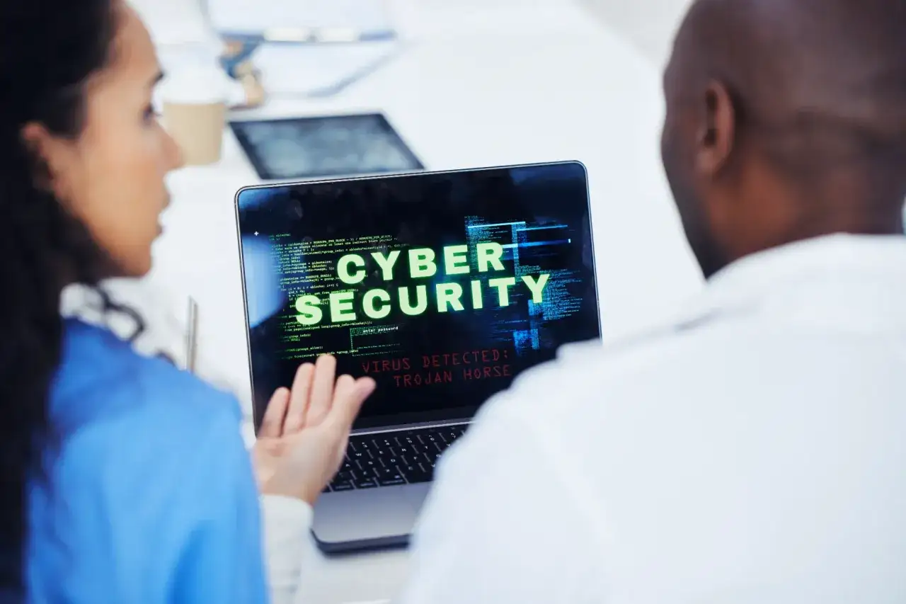 Due professionisti analizzano un avviso di sicurezza informatica su un laptop: