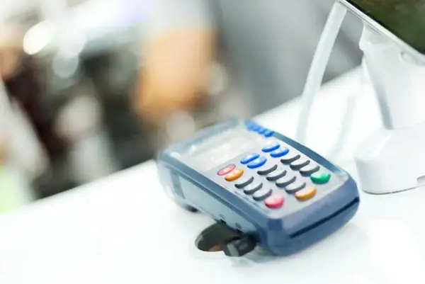 POS per chi non è obbligatorio. Un lettore di carte di credito su un bancone bianco, con uno schermo e tasti colorati.